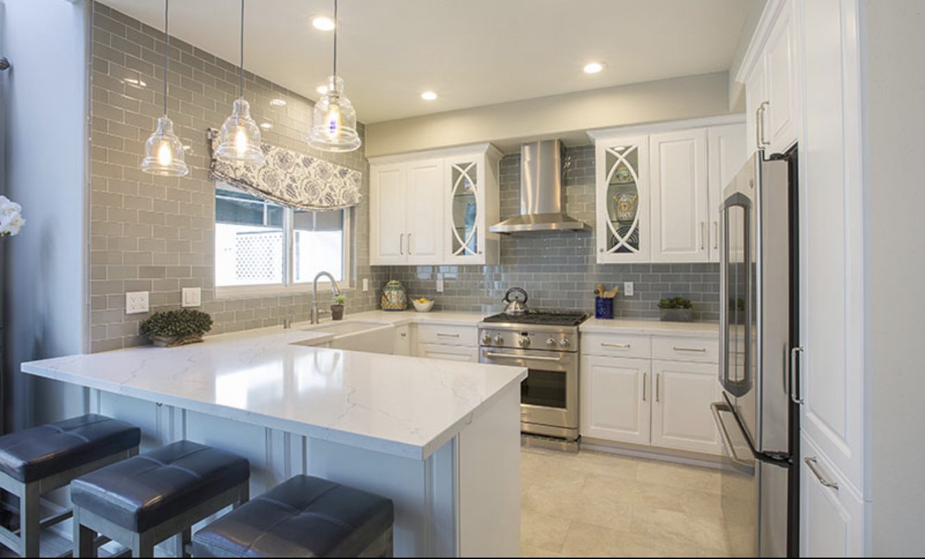 Contemporary kitchen remodel with white cabinets, gray subway tile backsplash, white stone counters, stainless appliances, by Seneca Contracting.