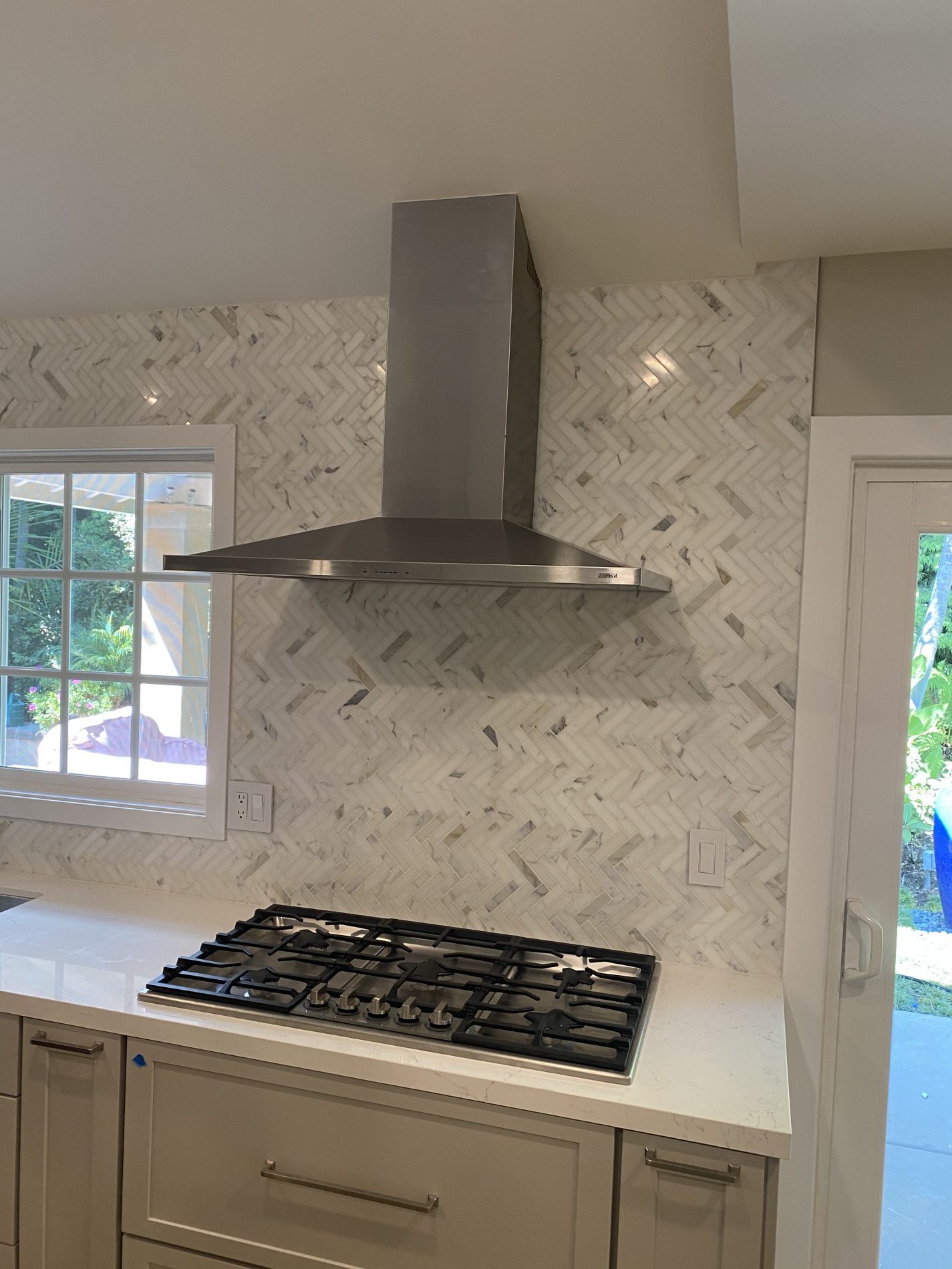Seneca contemporary gray, cream, farmhouse, open plan kitchen with wood beam, island, shelves, herringbone tile backsplash.